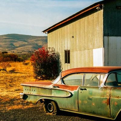 Derelict car beside a barn